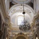 Dal soffitto dai toni celeste e oro scende un grande lampadario di cristallo